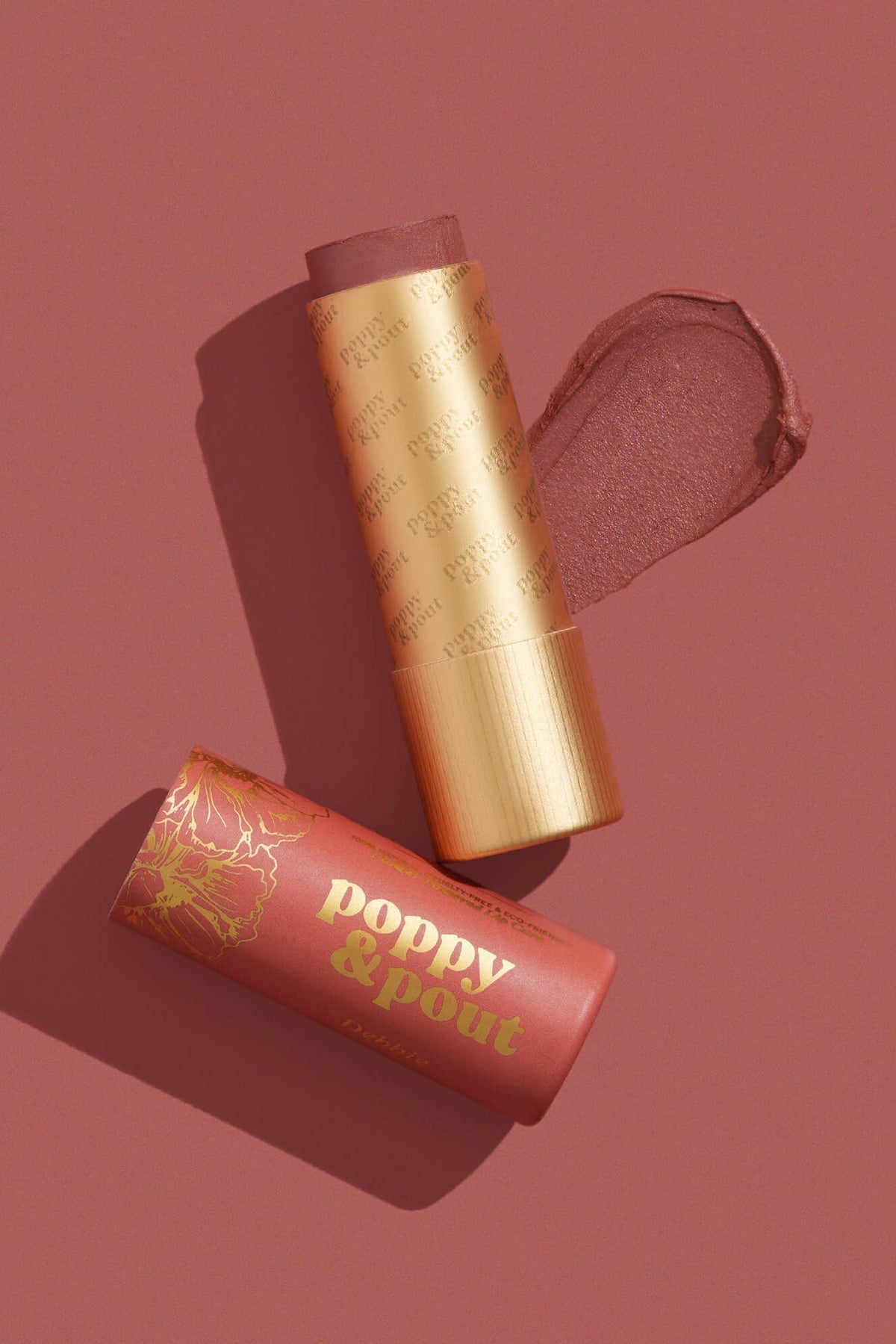 Makeup stick with gold cap and red casing on a maroon background