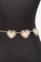 Gold heart-shaped belt on a black mannequin against a white background