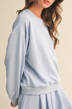Woman wearing a light blue sweatshirt and skirt set on a beige background
