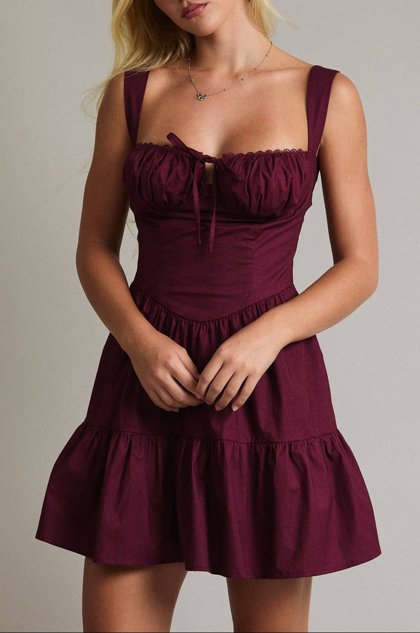 Woman wearing a burgundy dress against a plain background