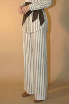 Woman wearing a striped outfit with a belt against a beige background