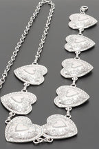 A silver heart-link chain necklace with multiple engraved heart charms, displayed on a dark gray background.