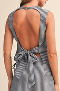 Woman wearing a striped top with an open back on a beige background