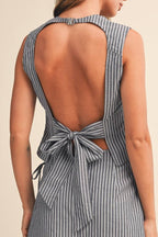 Woman wearing a striped top with an open back on a beige background