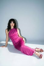 Woman in a pink dress sitting on a white surface with a light blue background