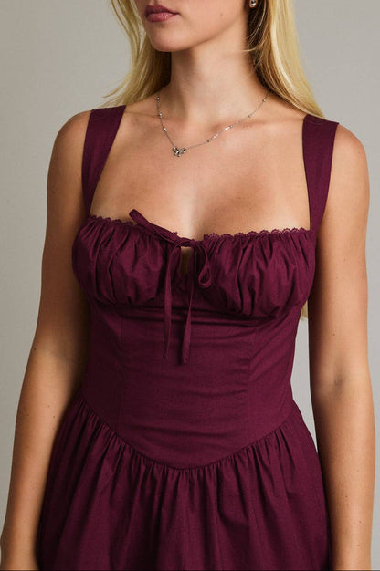 Woman wearing a burgundy dress against a neutral background