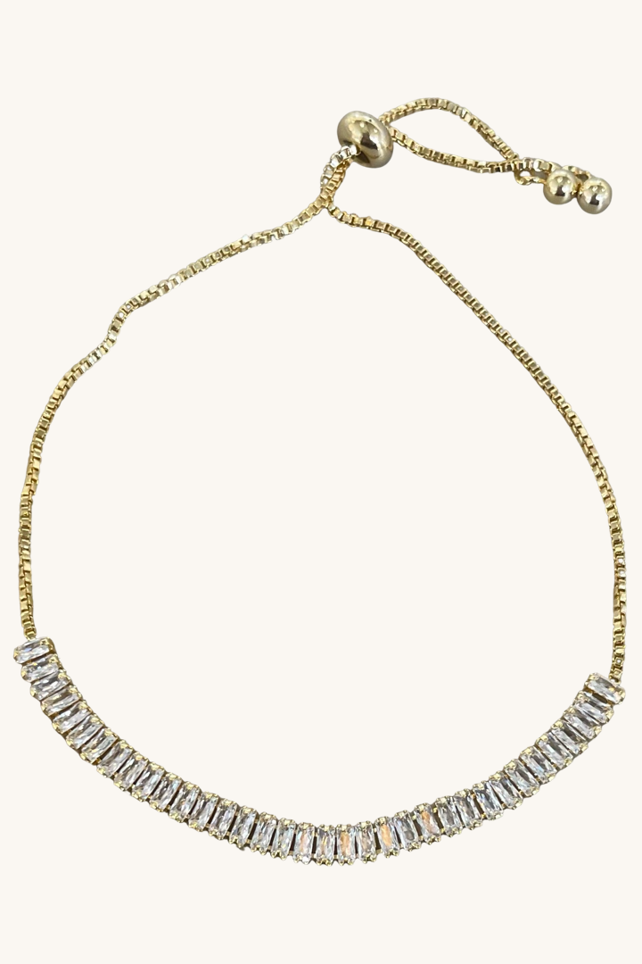 Gold bracelet with clear gemstones on a white background