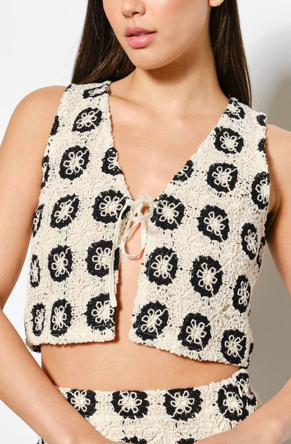 Woman wearing a patterned sleeveless top and skirt set against a white background