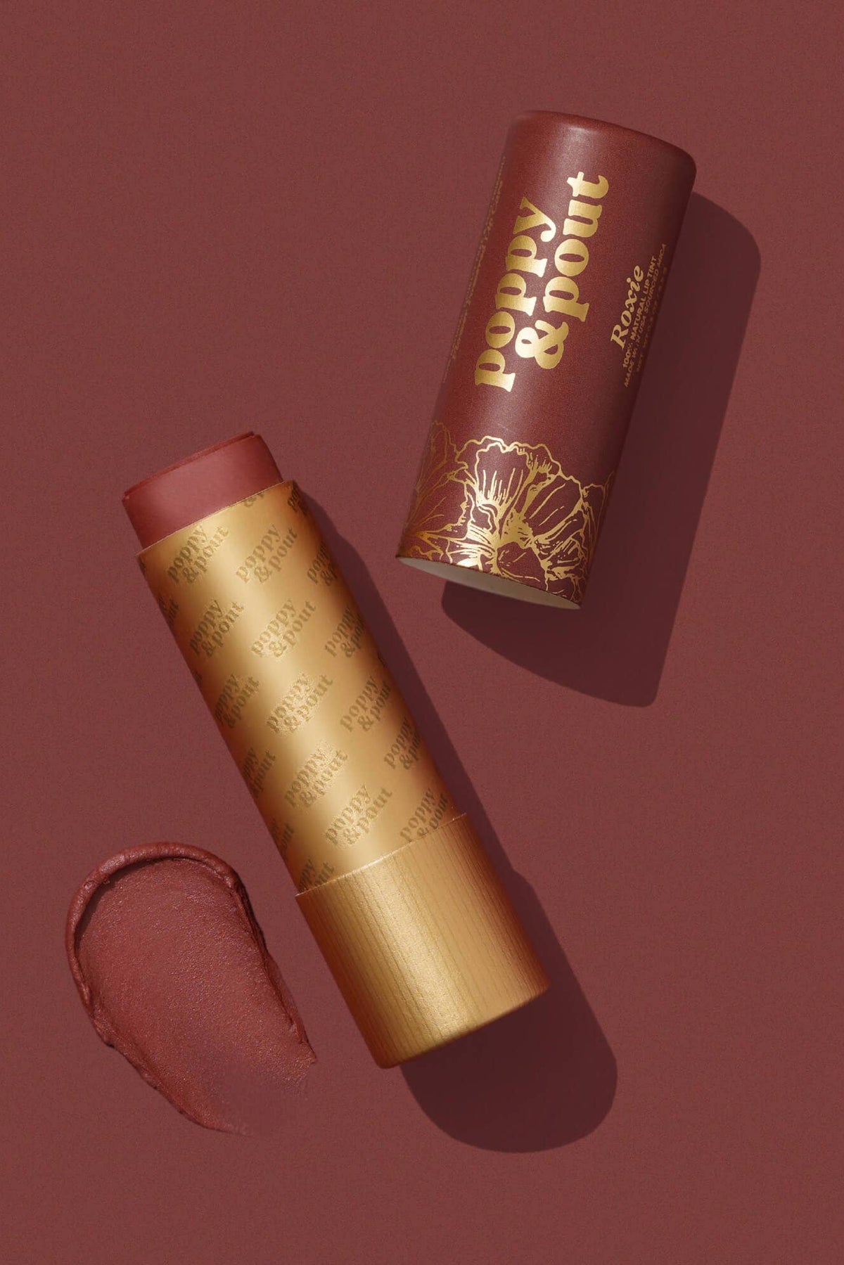 Lipstick with gold casing and brown shade on a matching background, featuring the brand 'Poppy & Point'.