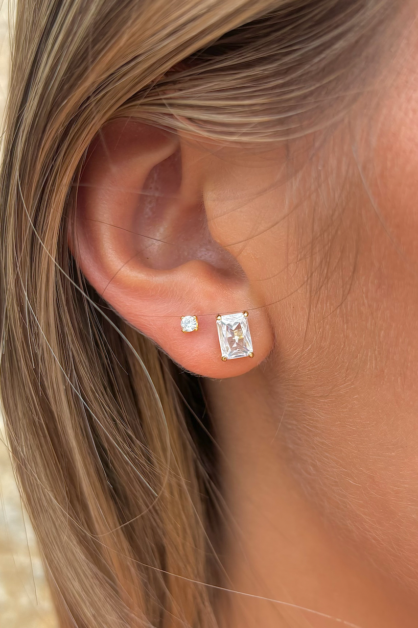 Close-up of an ear wearing diamond stud earrings with a blurred natural background