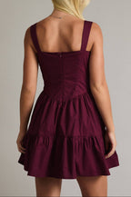 Woman wearing a burgundy dress with thin straps on a plain background