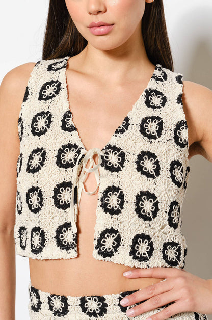 Woman wearing a black and ecru patterned outfit against a plain background