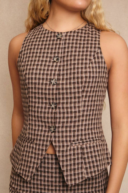 Brown checkered sleeveless top worn by a person against a neutral background