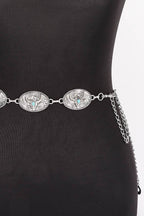 A silver western-style belt with three oval engraved medallions and a hanging chain, displayed on a black mannequin torso against a white background.