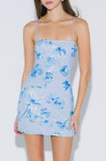 Woman wearing a light blue floral dress on a white background