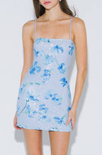 Woman wearing a light blue floral dress on a white background