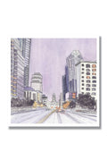 A watercolor-style cityscape print showing tall buildings, a wide road with cars, and a domed government building in the distance under a pale lavender sky, presented on a white background with a drop shadow.