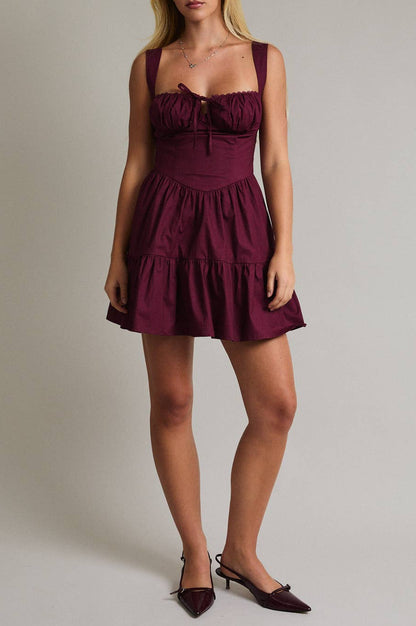 Woman wearing a burgundy dress against a plain background