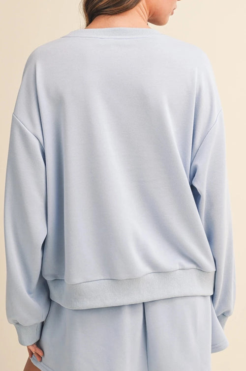 Light blue sweatshirt and shorts set on a beige background