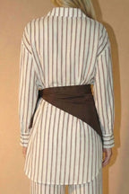 Person wearing a striped top with a brown scarf against a beige background