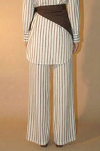 Person wearing a striped pant with a brown scarf on a beige background