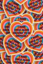 Heart-shaped stickers with colorful design and text 'I have once again decided to be difficult' on a multicolored background.
