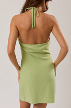 Woman wearing a green dress with thin straps on a plain background