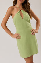 Woman wearing a light green halter neck dress against a plain background