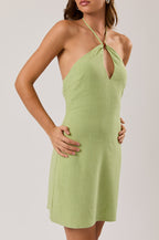 Woman wearing a green halter neck dress against a plain background