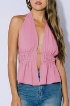 Woman wearing a pink halter top and blue jeans against a white background