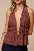 Woman wearing a brown halter top and navy shorts on a beige background
