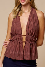 Woman wearing a brown halter top and navy shorts on a beige background