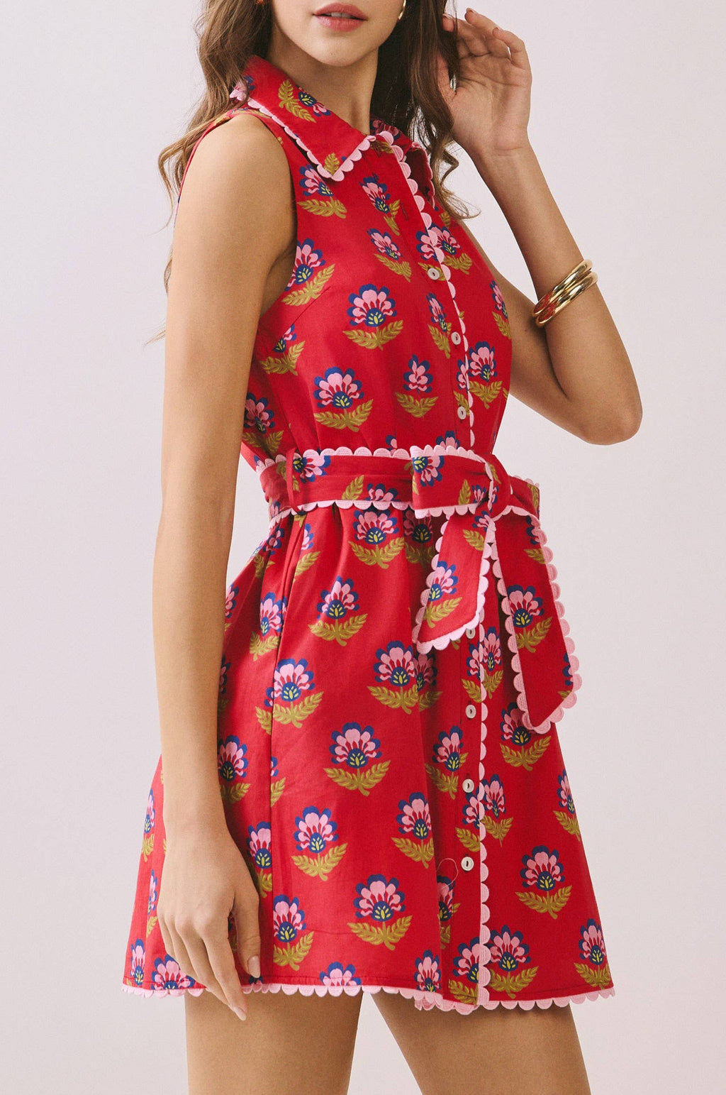 Woman wearing a red floral dress on a light pink background