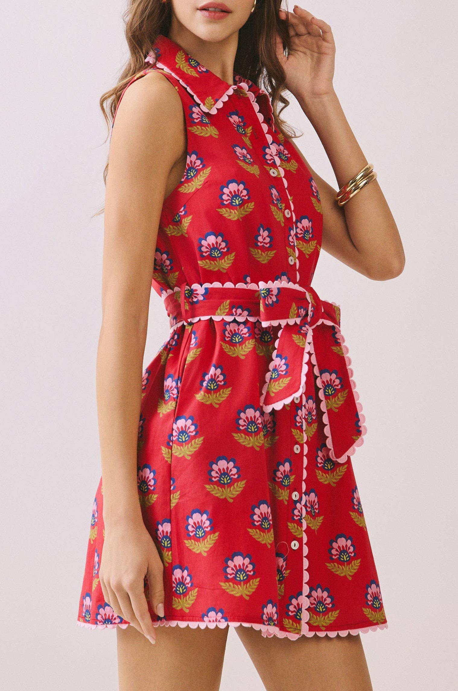 Woman wearing a red floral dress on a light pink background