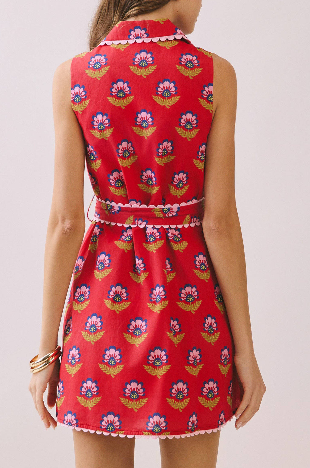 Woman wearing a red floral dress against a plain background
