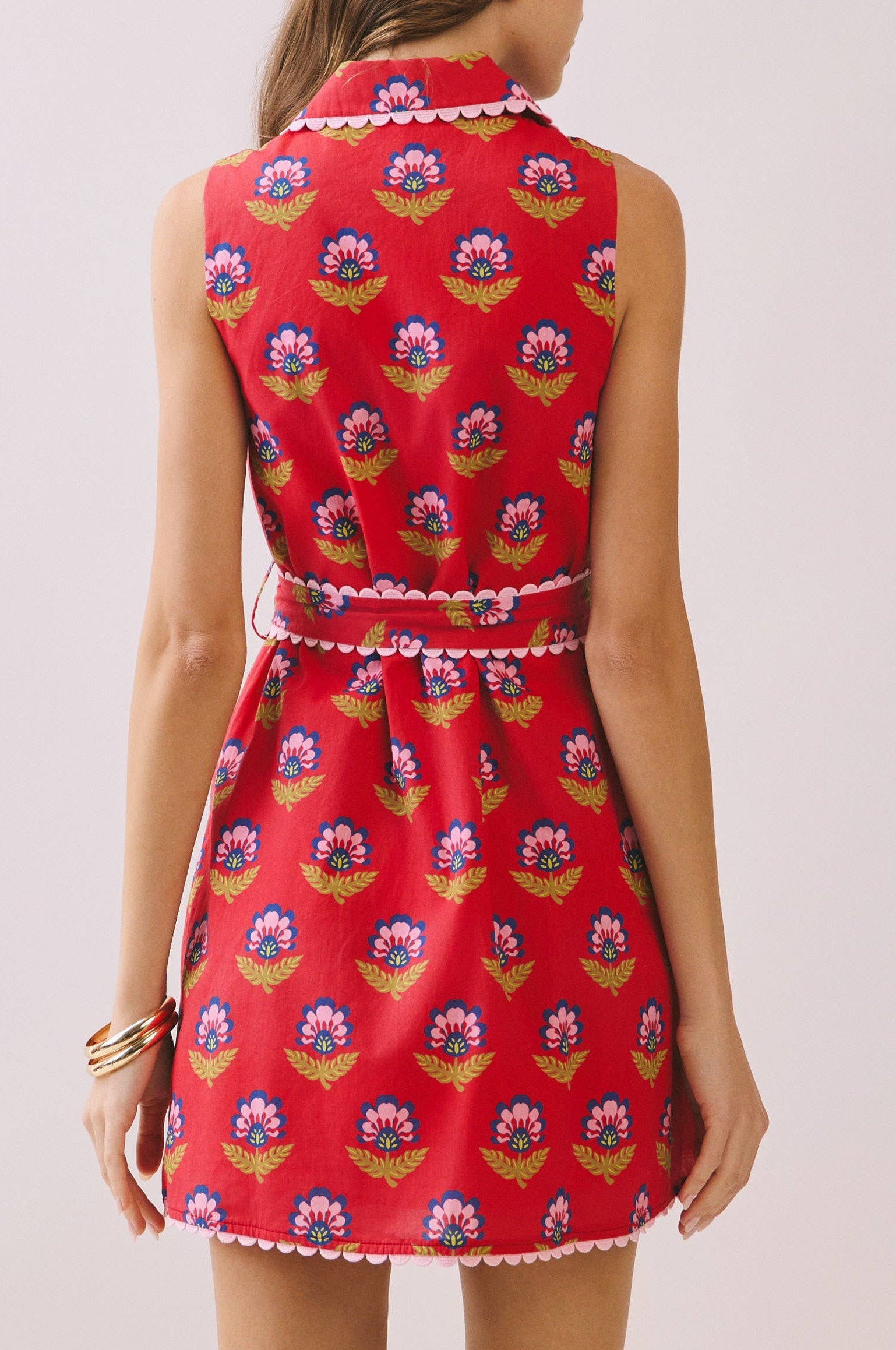 Woman wearing a red floral dress against a plain background