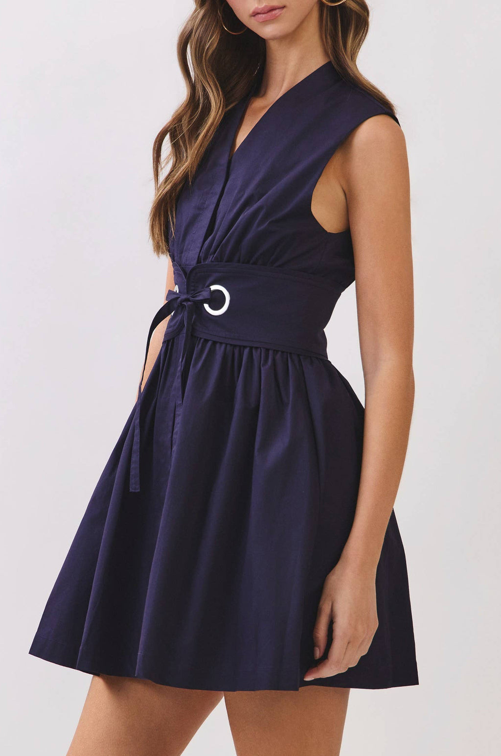 Woman wearing a navy blue dress with a belt on a white background