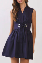 Woman wearing a navy sleeveless dress with a belt on a white background