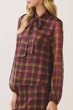 A woman modeling a matching plaid long-sleeve blouse and skirt set. The fabric features a classic tartan pattern in deep burgundy, brown, and muted green.