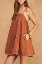 Woman wearing a brown dress against a beige background