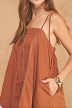 Woman wearing a brown dress with a beige background