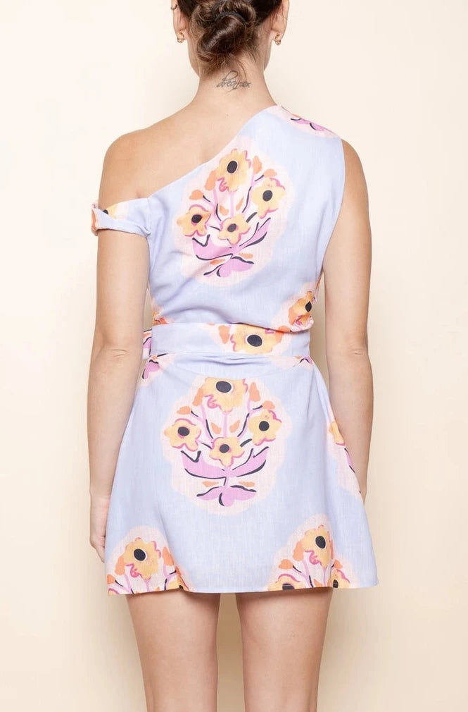 Woman wearing a floral one-shoulder dress against a beige background