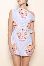 Woman wearing a light blue dress with floral patterns on a beige background
