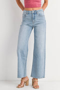 Woman wearing a pink sleeveless top and light blue jeans on a white background