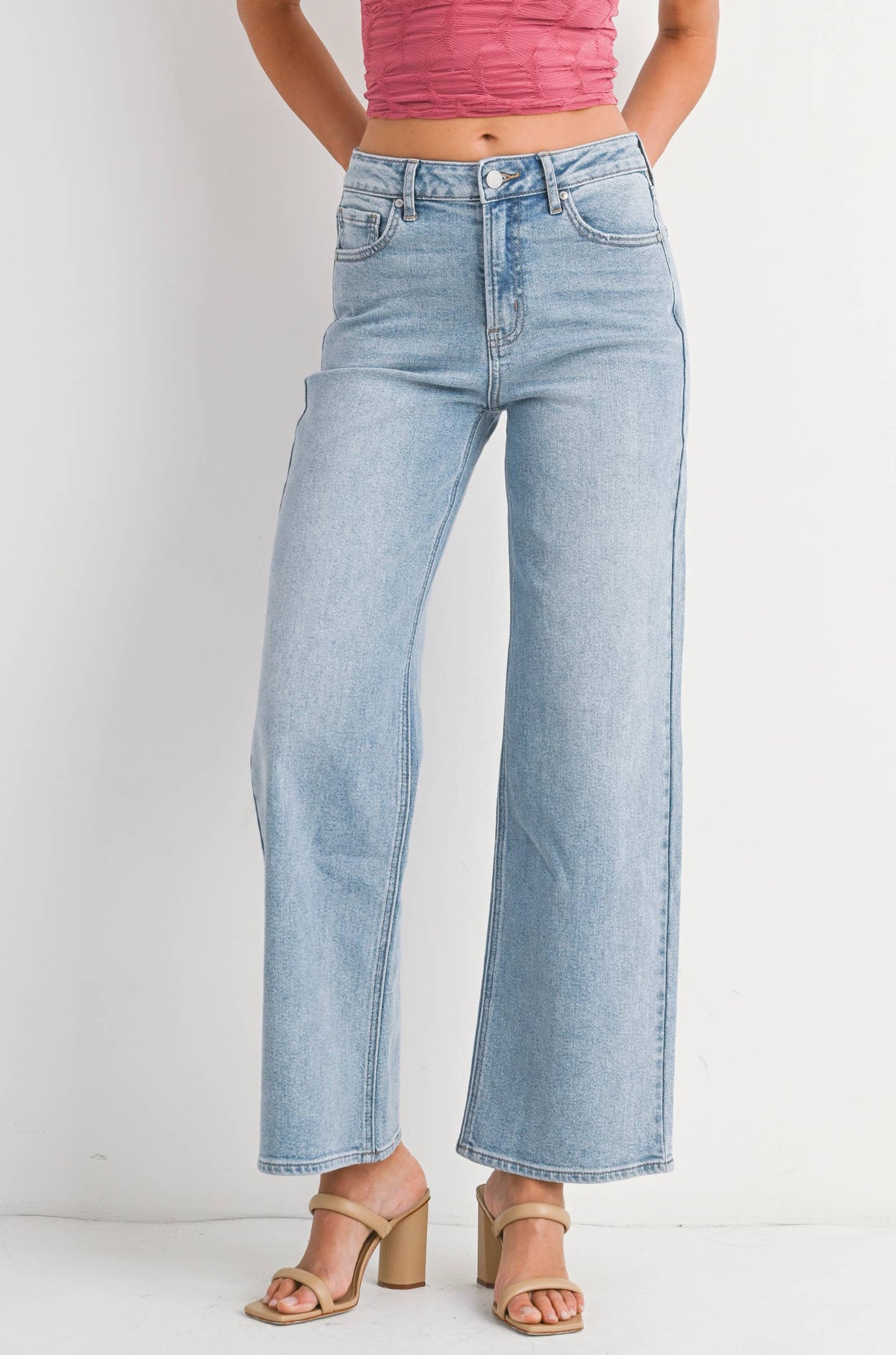Woman wearing a pink sleeveless top and light blue jeans on a white background