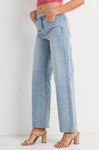 Woman wearing a pink halter top and light blue jeans on a white background