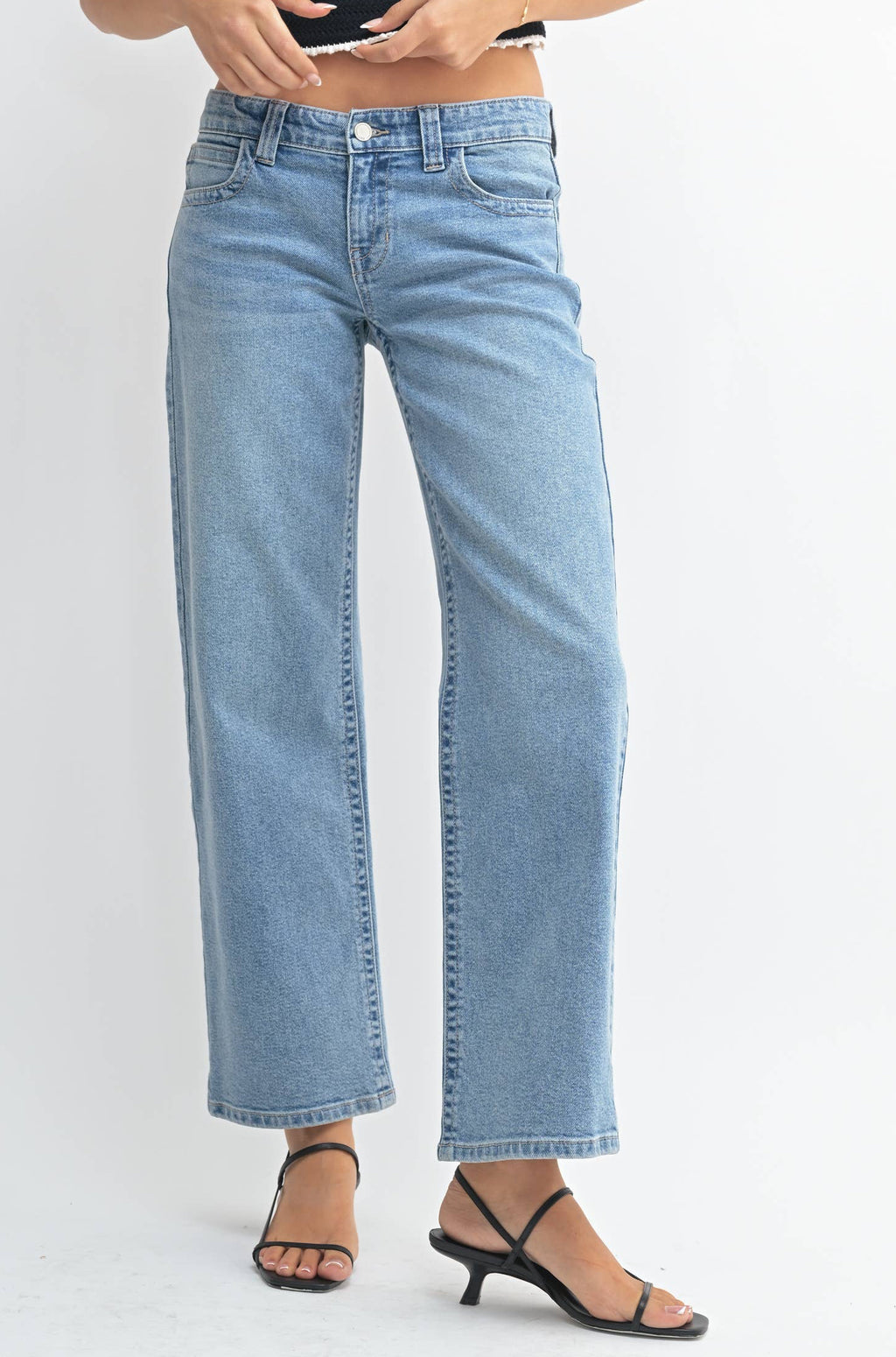 Woman wearing a black tank top and light blue jeans on a white background