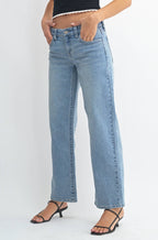 Woman wearing a black top and blue jeans on a white background