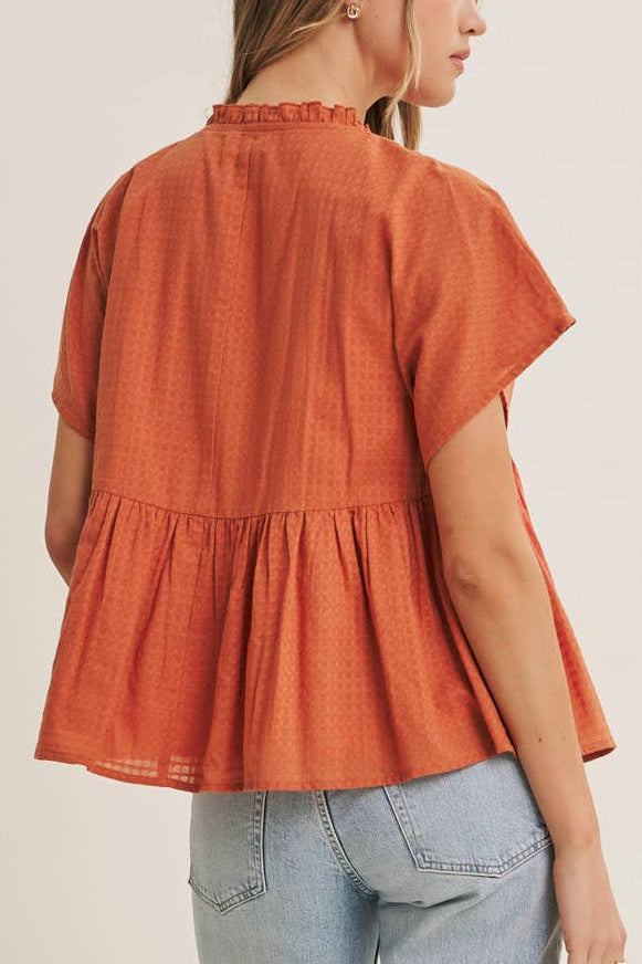 Woman wearing an orange blouse and light blue jeans on a beige background