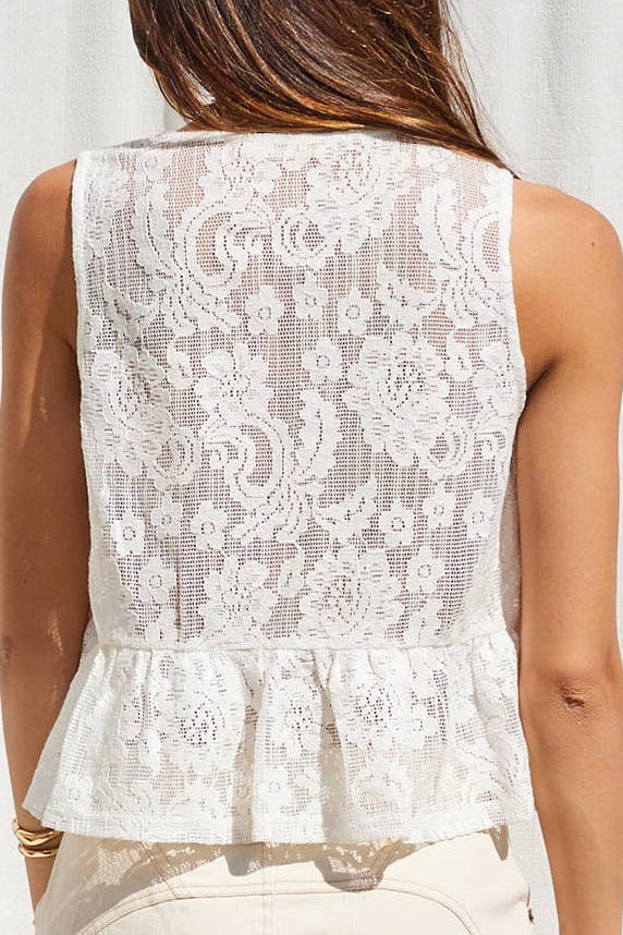 Woman wearing a white lace top against a white curtain background
